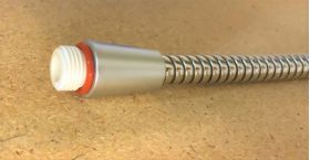 Fleksibel vannslange vises i metallfarge på brun lysebrun bakgrunn.