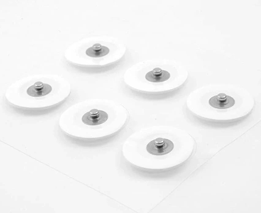 Nærbilde av Ultratone pads. Pads er runde, hvite og med sølvbit i midten.
