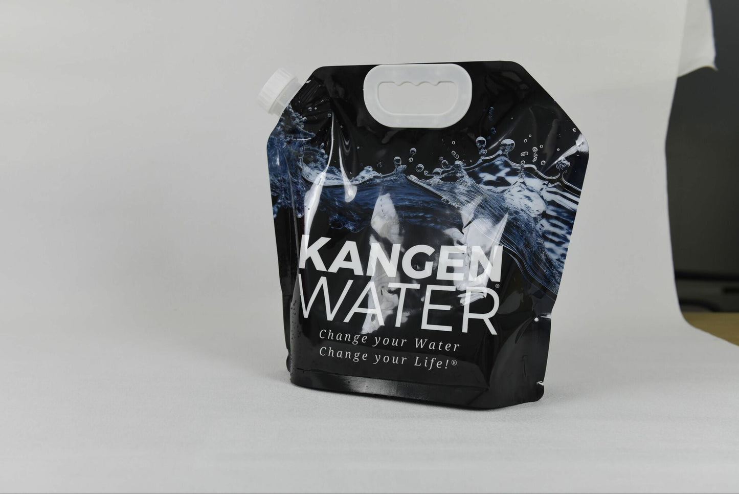 Mørk plastpose til vann, med hvit logo på framsiden. Posen har detaljer av bølgende vann. Hvit bakgrunn.