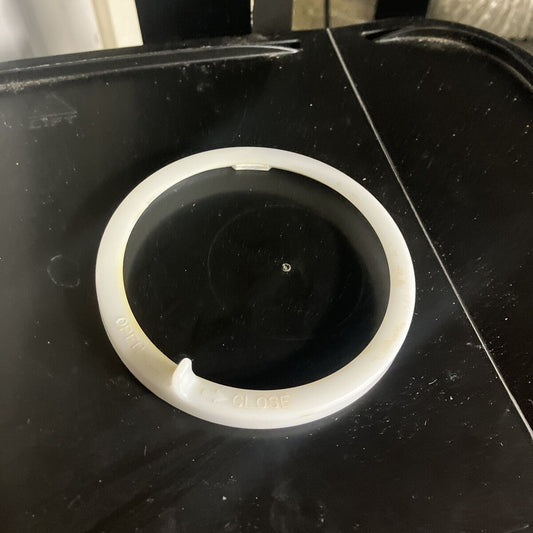 Hvit filterring i plast vises på et mørkt bord.